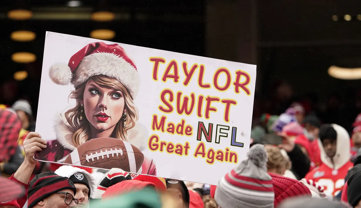 Poster bertuliskan "Taylor Swift membuat NFL hebat lagi" dari seorang fans saat pertandingan NFL (National Football League) antara Kansas City Chiefs melawan Las Vegas Raiders di Arrowhead Stadium, Kansas, Amerika Serikat, Selasa (26/12/2023) WIB. (AP Photo/Charlie Riedel)
