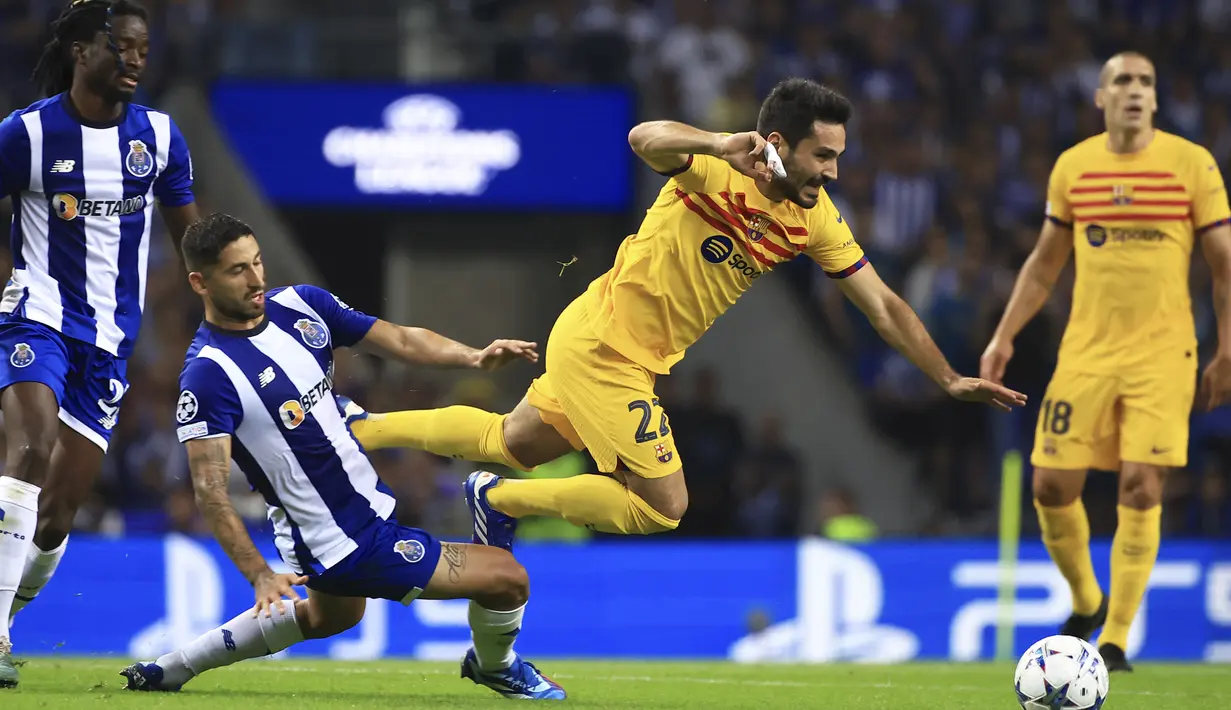 Pemain Barcelona, Ilkay Gundogan, terjatuh saat berusaha melewati pemain FC Porto, Alan Varela, pada laga matchday 2 Liga Champions 2023/2024 di Estadio do Dragao, Kamis (5/10/2023). Barcelona menang dengan skor tipis 1-0. (AP Photo/Luis Vieira)