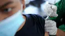 Seorang pemuda menerima vaksin virus corona COVID-19 AstraZeneca di klinik vaksinasi massal darurat di Denpasar, Bali, Selasa (6/7/2021). Indonesia tengah memerangi gelombang infeksi baru yang belum pernah terjadi sebelumnya. (SONNY TUMBELAKA