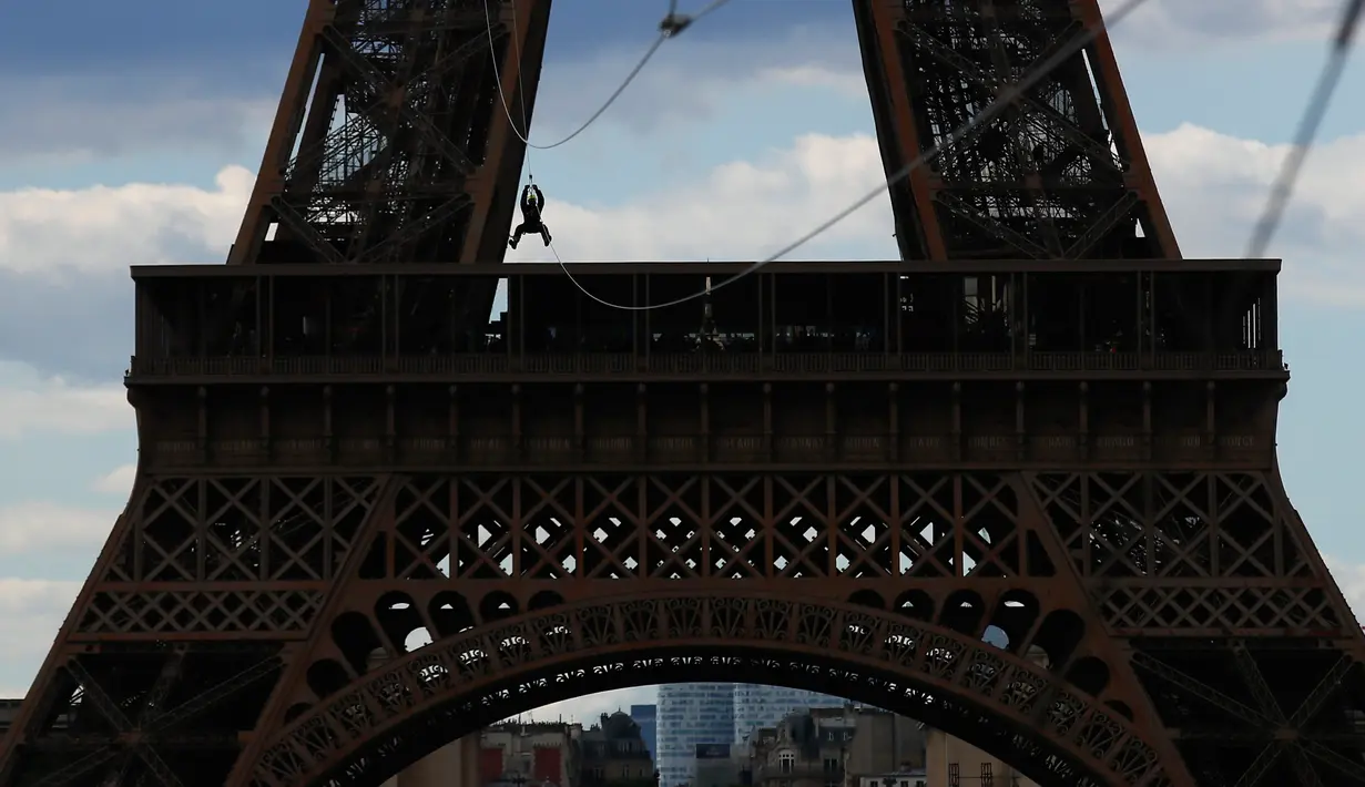 Pengunjung meluncur dengan seutas tali saat melakukan permainan Zip Line dari lantai dua Menara Eiffel di atas taman Champ de Mars, Paris, Selasa (28/5/2019). Kegiatan yang mirip dengan flying fox ini dipasangkan di atas ketinggian 115 meter dengan kecepatan 30 km per jam. (AP/Francois Mori)