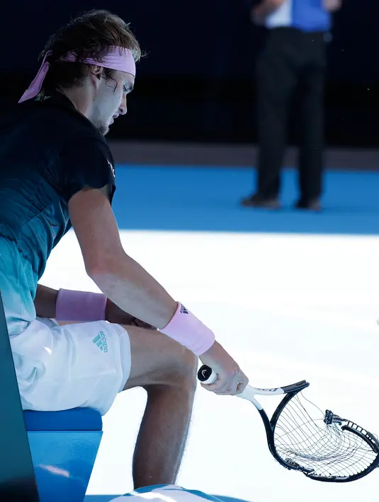 Petenis Jerman, Alexander Zverev merusak raketnya saat beristirahat pada putaran keempat Australia Terbuka  menghadapi petenis Kanada, Milos Raonic di Melbourne, Senin (21/1). Zverev frustasi setelah kalah dua set 6-1 4-1. (AP/Aaron Favila)