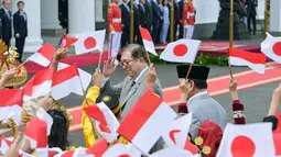 Kedatangan PM Shigeru Ishiba lalu disambut murid sekolah yang mengibarkan bendera Indonesia dan Jepang sambil mengucapkan kalimat selamat datang dalam bahasa Jepang. (Bay ISMOYO/AFP)