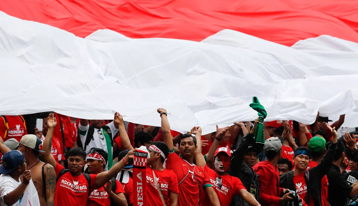 Suporter Timnas Indonesia U-22 membentangkan bendera merah putih saat menyaksikan pertandingan melawan Thailand di SEA Games 2017 di Shah Alam, Malaysia (15/8). Indonesia dan Thailand bermain imbang 1-1. (AP Photo / Vincent Thian)