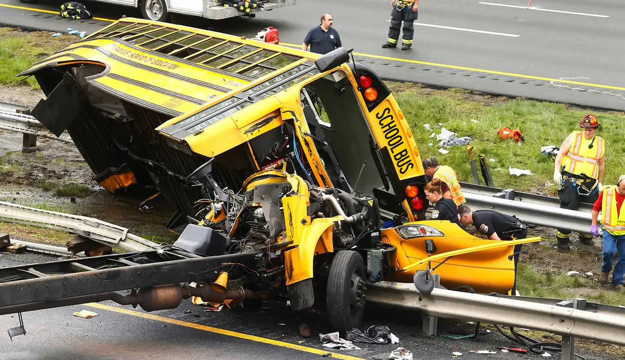 Personel darurat memeriksa kondisi bus sekolah yang bertabrakan dengan truk sampah di Interstate 80, Mount Olive, New Jersey, Kamis (17/5). Belum diketahui penyebab kecelakaan yang menewaskan sedikitnya 2 orang tersebut. (Bob Karp/The Daily Record via AP)