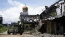 Tentara menaiki truk melewati bangunan yang hancur di Kota Marawi, Mindanao, Filipina, 23 Mei 2019. Kota yang sempat dikuasai ISIS tersebut tetap menjadi reruntuhan, para ahli pun memperingatkan bahwa upaya rekonstruksi yang macet memperkuat daya tarik kelompok ekstremis. (Noel CELIS/AFP)