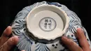 Pekerja memperlihatkan bagian bawah mangkuk Xuande Lobel "Fish Pond" saat ditampilkan di pelelangan Sotheby di Hong Kong (8/3). Mangkuk Xuande Lobel "Fish Pond" ini akan dilelang pada tanggal 5 April. (AP Photo / Kin Cheung)