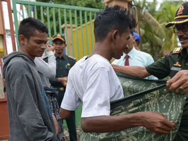 Polisi Syariat Islam memakaikan kain sarung pada warga bercelana pendek saat razia penertiban hukum syariat islam di Banda Aceh, Aceh, Selasa (19/9). Razia digelar sebagai implementasi Qanun Aceh No 11 Tahun 2002. (CHAIDEER MAHYUDDIN/AFP)