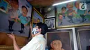 Seorang pelukis memacang lukisan tokoh-tokoh nasional di Depan Pasar Baru, Jakarta, Kamis (24/12/2020). Para pelukis memasarkan lukisannnya dengan harga bervariasi dari dari Rp 500 ribu hingga Rp 2,5 juta. (merdeka.com/Dwi Narwoko)