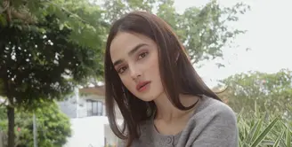 Syifa tampil mengenakan atasan cardigan abu-abu dipadukan celana hitam panjang. Rambut panjang kecoklatannya dibiarkan terurai dengan wajah dipulas makeup warm. [@syifahadju]