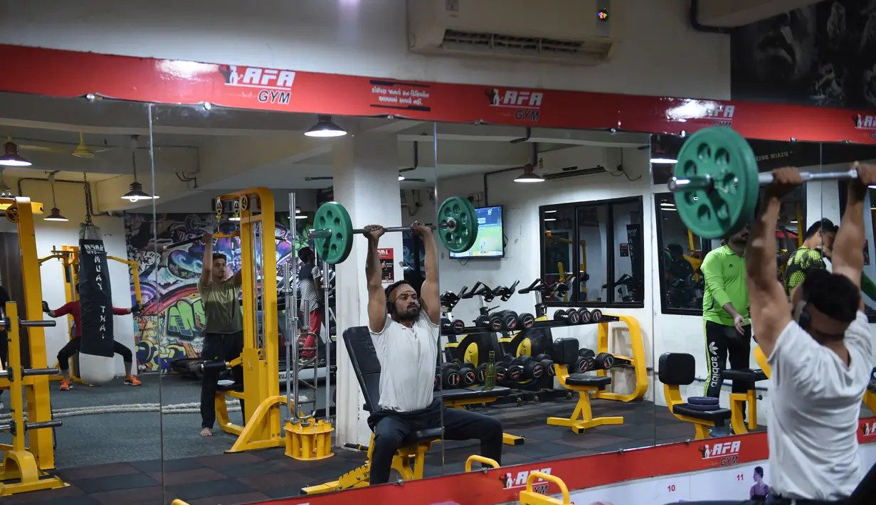 Seorang pria India saat berlatih di gym Ahmedabad Fitness Academy (AFA) di Ahmedabad (10/5/2019). Selama bulan suci Ramadhan, tempat gym ini tetap buka hingga larut malam untuk membiarkan anggota Muslim berolahraga setelah salat. (AFP Photo/Sam Panthaky)
