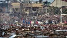 Orang-orang melihat rumah-rumah yang hancur akibat ledakan yang mengoyak gudang kembang api, di distrik Sungai Kolok di provinsi Narathiwat, Thailand selatan, pada 29 Juli 2023. (Madare TOHLALA / AFP)