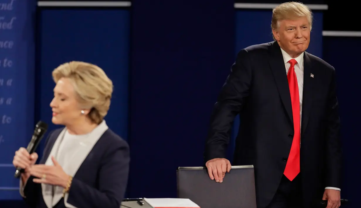 Tingkah aneh Donald Trump pada saat rivalnya, Hillary Clinton memaparkan pendapatnya selama debat Capres AS putaran kedua di Washington University, St Louis, AS, Minggu (9/10). (AP Photo/Julio Cortez)