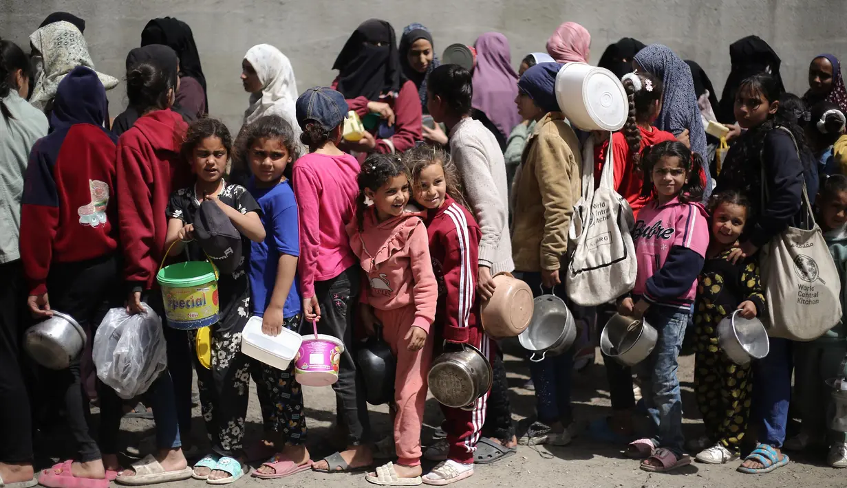 Beberapa anak-anak antre bersama orang dewasa untuk mendapatkan pembagian makanan gratis di kamp pengungsi Nuseirat, Jalur Gaza tengah, pada 3 April 2025. (Eyad BABA/AFP)