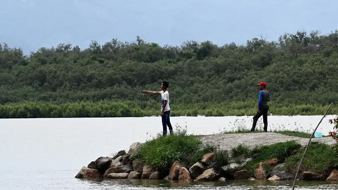Gambar yang diambil pada 7 Juni 2020 ini menunjukkan para pria yang sedang memancing dari pantai di desa nelayan Pulau Betong di Penang, Malaysia. (GOH CHAI HIN / AFP)
