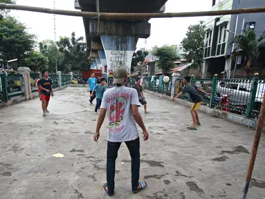 Sejumlah remaja bermain sepak bola di kolong rel kereta kawasan Juanda, Jakarta, Jumat (27/5). Tidak tersedianya ruang terbuka menyebabkan lahan tersebut dijadikan tempat bersosialisasi bagi warga. (Liputan6.com/Immanuel Antonius)