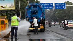 Petugas menyemprotkan air ke pohon-pohon untuk mengurangi polusi udara di pinggir jalan New Delhi, Rabu (6/11/2019). Tingkat polusi udara di Ibu Kota India itu kian memburuk, hingga mengancam kesehatan masyarakat. (Photo by Prakash SINGH / AFP)