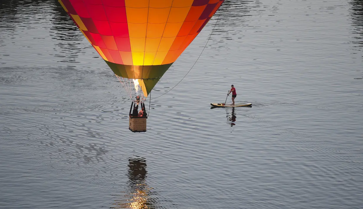 Pedayung saat melihat balon udara yang terbang diatas danau Burley Griffin, Canberra,  Australia, (15/3). Ini dilakukan dilakukan dalam memperingati ulang tahun ke-30 festival Balloon Spectacular Canberra . (REUTERS / Lukas Coch)