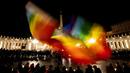 Seseorang mengibarkan bendera pelangi saat orang-orang yang percaya berdoa untuk perdamaian Ukraina di Lapangan Santo Petrus, Vatikan, 2 Maret 2022. (Tiziana FABI/AFP)