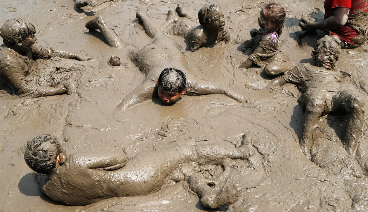 Anak-anak berendam dalam lumpur saat berpartisipasi dalam Mud Day atau Hari Lumpur di Michigan, negara bagian AS, Selasa (9/7/2019). Para peserta perayaan yang menjadi tradisi setiap tahun ini merupakan anak-anak untuk agar mereka bersenang-senang selama liburan musim panas.  (AP/Carlos Osorio)