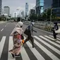 Sejumlah pekerja berjalan melintas pelican cross di kawasan Jalan Sudirman, Jakarta, Selasa (2/11/2021). Sektor non-esensial kini boleh mempekerjakan hingga 75 persen karyawannya dari kantor. Sebelumnya, angka ini dibatasi hingga 50 persen. (Liputan6.com/Faizal Fanani)