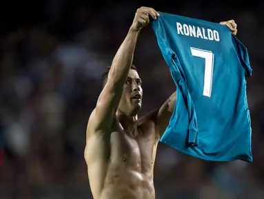 Pemain Real Madrid, Cristiano Ronaldo berselebrasi dengan melepas dan mengangkat jerseynya di hadapan suporter Camp Nou pada leg pertama Piala Super Spanyol, Senin (14/8). Selebrasi itu dilakukan usai Ronaldo membobol gawang Barcelona. (STRINGER/AFP)