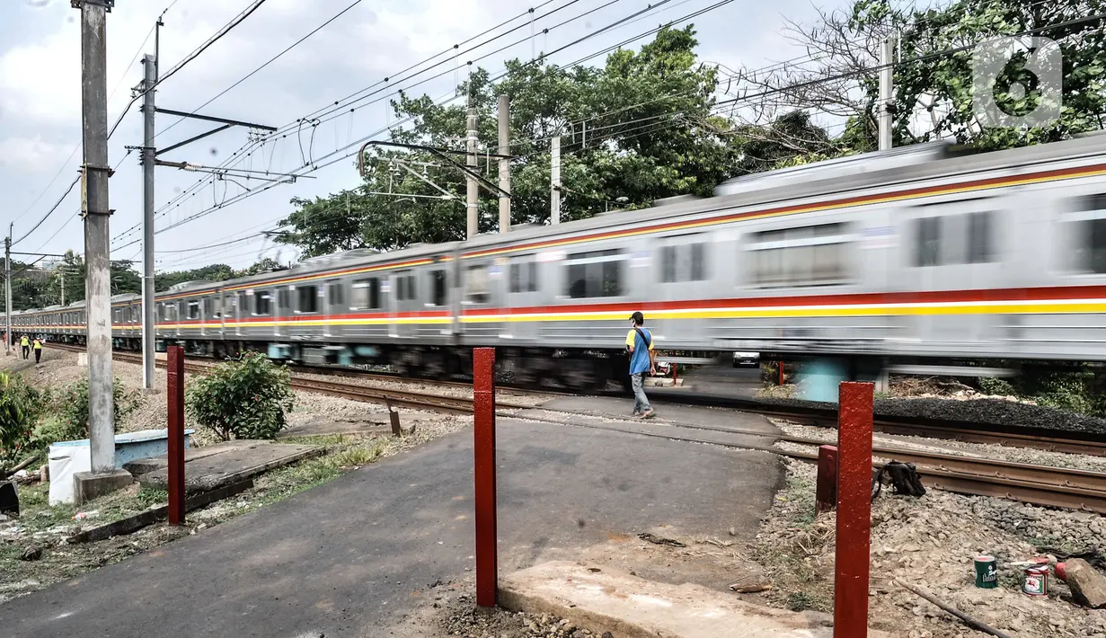 Warga saat mengatur lalu lintas kendaraan di perlintasan kereta tanpa palang pintu di kawasan TPU Tanah Kusir, Jakarta, Kamis (17/9/2020). Pemasangan pembatas jalan tersebut dilakukan untuk mencegah kecelakaan kendaraan yang sering terjadi di kawasan tersebut. (merdeka.com/Iqbal S. Nugroho)