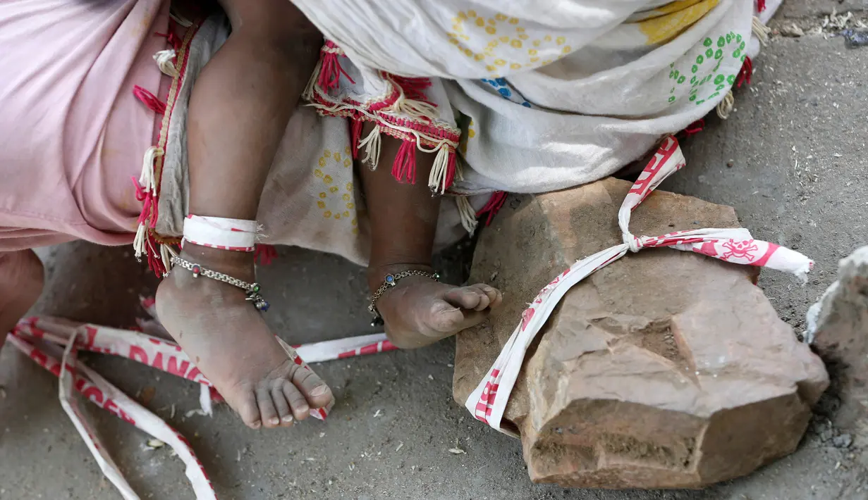 Kaki Shivani (15 bulan) terikat pada batu di bangunan di Ahmedabad, India, 20 April 2016. Dengan bertelanjang kaki, bayi itu menghabiskan 9 jam/hari di bawah suhu udara mencapai 40 derajat Celsius terikat pada tali sepanjang 1,4 meter. (REUTERS/Amit Dave)