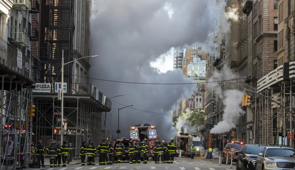 Petugas pemadam kebakaran berada di lokasi meledaknya pipa uap di Fifth Avenue dekat Distrik Flatiron, Manhattan, Kamis (19/7). Departemen Kepolisian New York menyarankan orang-orang menjauhi area itu demi alasan keamanan. (Drew Angerer/Getty Images/AFP)