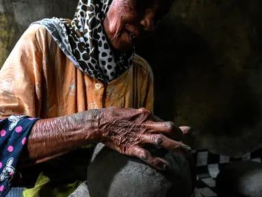 Seorang pembuat tembikar membuat pot tanah liat menggunakan tangan dalam bengkel rumah di Banda Aceh, Aceh, Rabu (4/8/2021). (CHAIDEER MAHYUDDIN/AFP)