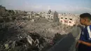 <p>Seorang anak melihat gedung-gedung yang hancur akibat bombardir Israel di Rafah, Jalur Gaza, Palestina, Minggu (22/10/2023). (AP Photo/Hatem Ali)</p>
