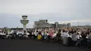 Para tamu melambai ke arah helikopter yang terbang di atas meja mereka saat acara “Berlin Freedom Dinner” di landasan pacu bekas bandara Tegel, Berlin pada 7 Agustus 2021. Acara itu untuk mengirim sinyal 'Berlin kembali!' setelah berbulan-bulan menghadapi pandemi COVID-19. (Tobias SCHWARZ/AFP)