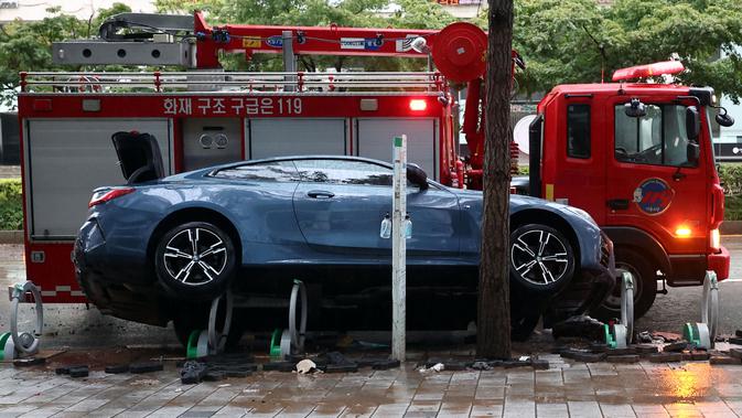 Sebuah mobil yang rusak akibat banjir terlihat di jalan setelah hujan deras di distrik Gangnam, Seoul pada Selasa (9/8/2022). Penduduk di daerah dataran rendah dievakuasi untuk keselamatan sementara bagian dari jalur kereta bawah tanah terpaksa berhenti.  (YONHAP / AFP)