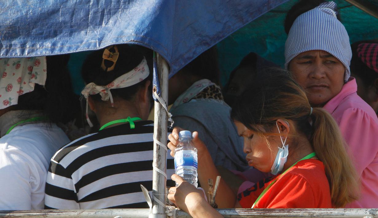 Para pekerja menaiki mobil bak terbuka sebagai transportasi harian mereka pulang ke rumah dari tempat kerja di sebuah pabrik di dekat desa Trapang Anchanh, di luar Phnom Penh, Kamboja (27/10). (AP Photo/Heng Sinith)