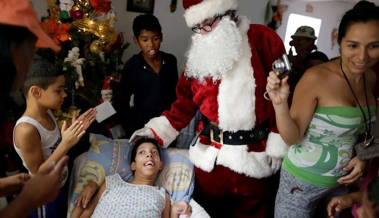 Santa Claus menghibur seorang anak berkebutuhan khusus saat mengunjungi kawasan kumuh Petare di Caracas, Venezuela (11/12). Kunjungan Santa Claus ini untuk menghibur anak-anak dalam menyambut datangnya natal. (Reuters/Ueslei Marcelino)