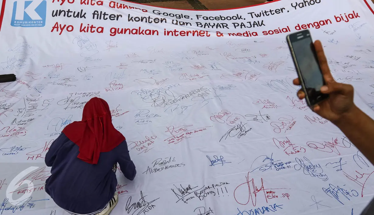 Seorang warga membubuhkan tanda tangan saat aksi penandatanganan spanduk dukungan bayar pajak di CFD Jalan MH Thamrin, Jakarta, Minggu (25/9). Dalam aksinya, mereka juga meminta media sosial untuk melakukan filter konten. (Liputan6.com/Fery Pradolo)