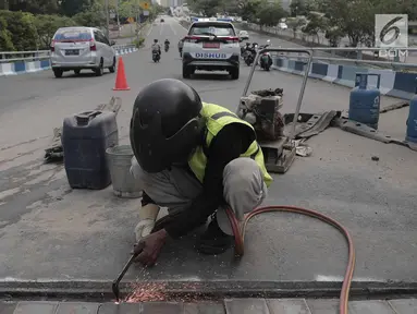 Para pekerja memperbaiki aspal di flyover Kemayoran yang mengalami kerenggangan, Jakarta, Sabtu (5/1). Hal itu disebabkan rusaknya sambungan celah sambungan alias expansion joint. (Merdeka.com/Imam Buhori)