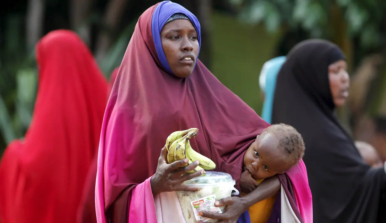 Seorang ibu sambil menggendong anaknya membawa iftar (makanan berbuka puasa) dari sebuah organisasi amal Qatar selama bulan suci Ramadan, di ibukota Mogadishu, Senin (22/6/2015). (REUTERS/Feisal Omar)