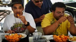 Dua orang peserta mencoba menyelesaikan makan cabai Habanero dalam Habanero Eating Contest di Restoran Chichen Itza, Los Angeles, Minggu (21/6). Dalam lomba ini setiap peserta diberikan 60 cabai Habanero dengan waktu 20 menit. (AFP PHOTO/Mark RALSTON)