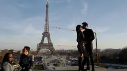 Sepasang suami istri berciuman pada Hari Valentine ketika mereka berdiri di Trocadero Plaza dekat Menara Eiffel di Paris, Prancis (14/2). (AFP Photo/Ludovic Marin)