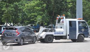Petugas Dishub DKI Jakarta menderek mobil yang terkena razia parkir liar di penampungan derek parkir liar, Monas, Jakarta, Senin (13/3). Pada periode Januari-Febuari, Dishub menindak 6.437 kendaraan dengan sanksi ditilang. (Liputan6.com/Yoppy Renato)