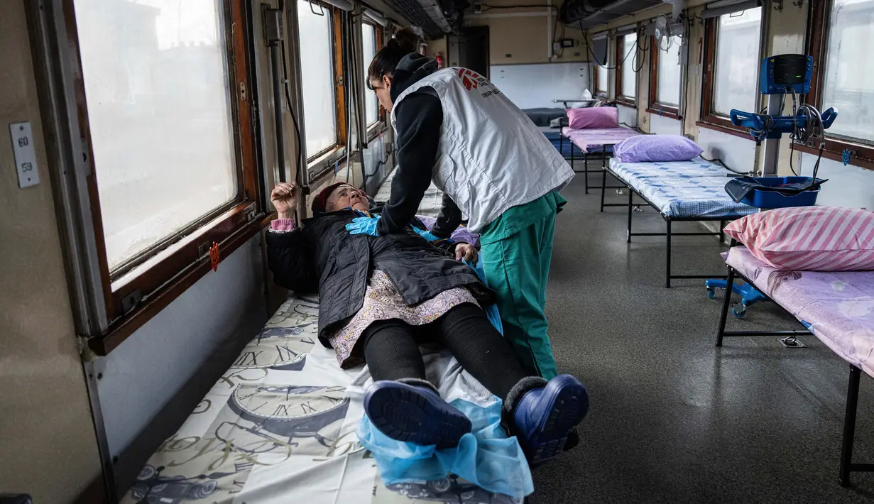 <p>Pekerja Medecins Sans Frontieres (MSF) atau Doctors Without Border berbicara kepada seorang wanita dalam kereta medis MSF saat mengevakuasi pasien dari dekat garis depan pertempuran ke daerah yang lebih aman di stasiun kereta di Pokrovsk, Ukraina, 7 Maret 2023. MSF merupakan kereta medis khusus yang dapat membawa pasien dari bagian timur Ukraina ke rumah sakit di bagian barat. (AP Photo/Evgeniy Maloletka)</p>