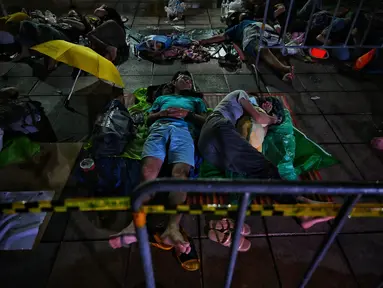 Warga tidur saat antre semalaman untuk tes swab Covid-19 gratis di Wat Phra Sri Mahathat Woramahawihan di Bangkok, Jumat (9/7/2021) dinihari. Thailand pada Kamis (8/7/2021), mencatat rekor 75 kematian Covid-19 dalam 24 jam terakhir, sehingga jumlah kematian menjadi 2.462. (Lillian SUWANRUMPHA/AFP)