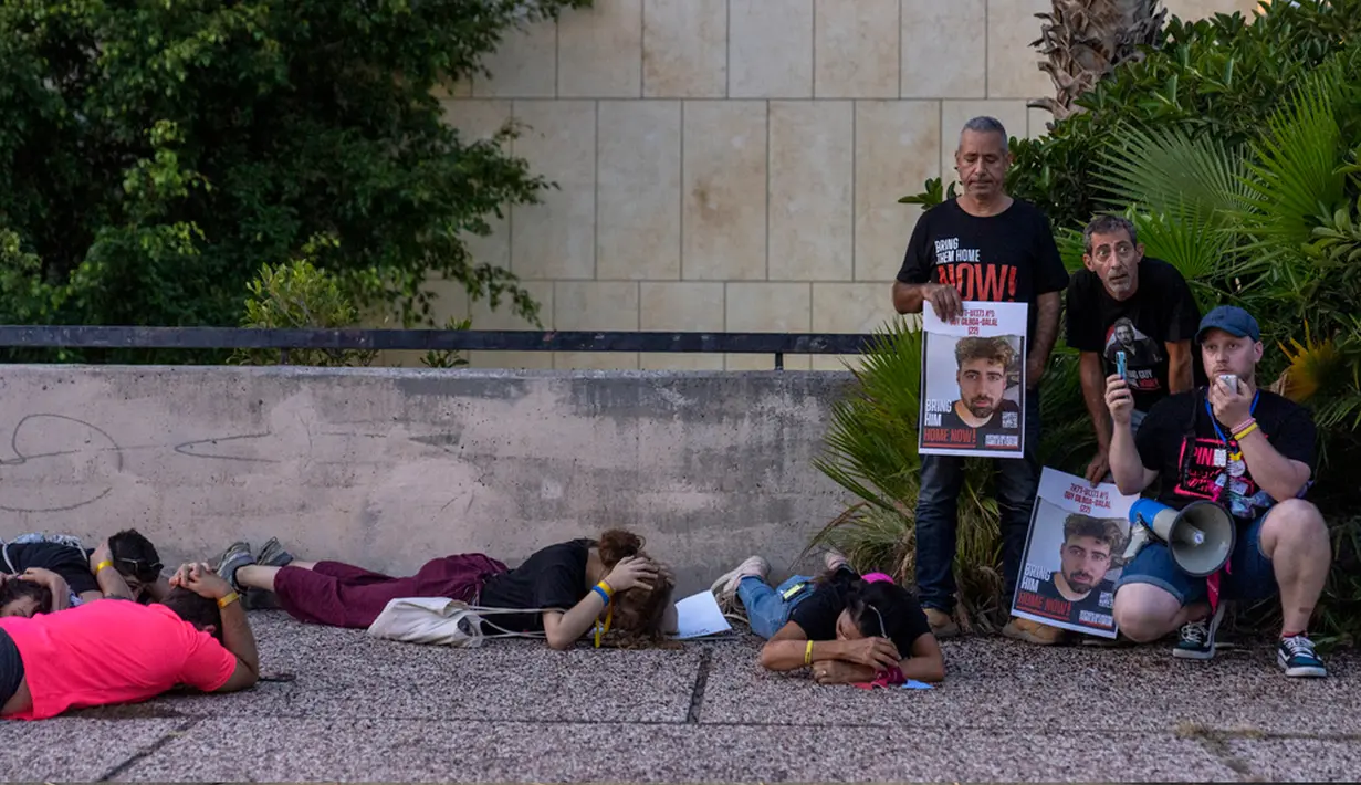 Warga berlindung saat sirene memperingatkan akan adanya roket yang ditembakkan dari Jalur Gaza, saat protes yang menyerukan kembalinya lebih dari 220 orang yang ditangkap oleh militan Hamas, di Tel Aviv, Israel, Kamis (26/10/2023). (AP Photo/Ohad Zwigenberg)