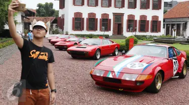 Pengunjung berfoto dengan latar belakang Ferrari klasik di Gedung Arsip Nasional, Jakarta, Selasa (14/3). Merayakan ulang tahun ke-70 keberadaan Ferrari di dunia otomotif, Ferrari Jakarta memboyong 10 supercar klasik pilihan. (Liputan6.com/Angga Yuniar)