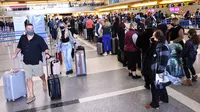 Pelancong berkumpul di terminal internasional Bandara Los Angeles (LAX) di tengah lonjakan kasus varian omicron, Selasa (21/12/2021). AAA memperkirakan lebih dari 109 juta orang Amerika akan melakukan perjalanan selama musim liburan antara 23 Desember dan 2 Januari. (MARIO TAMA/Getty Images via AFP)