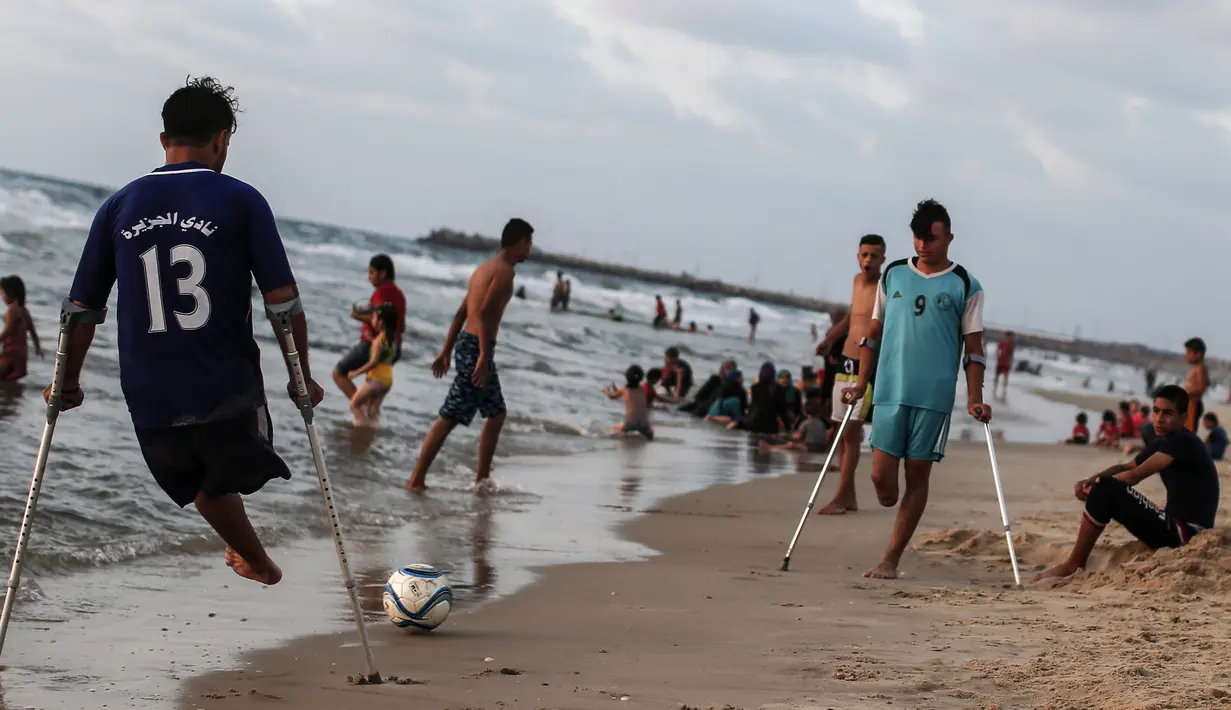 Dua pemuda Palestina Mohammed Eliwa (kanan) dan dan Ahmed al-Khoudari bermain sepak bola di pantai di Kota Gaza (20/9/2019). Eliwa 17 tahun dan Ahmed al-Khoudari 20 tahun kehilangan satu kakinya saat bentrok di perbatasan Israel. (AFP Photo/Mahmud Hams)