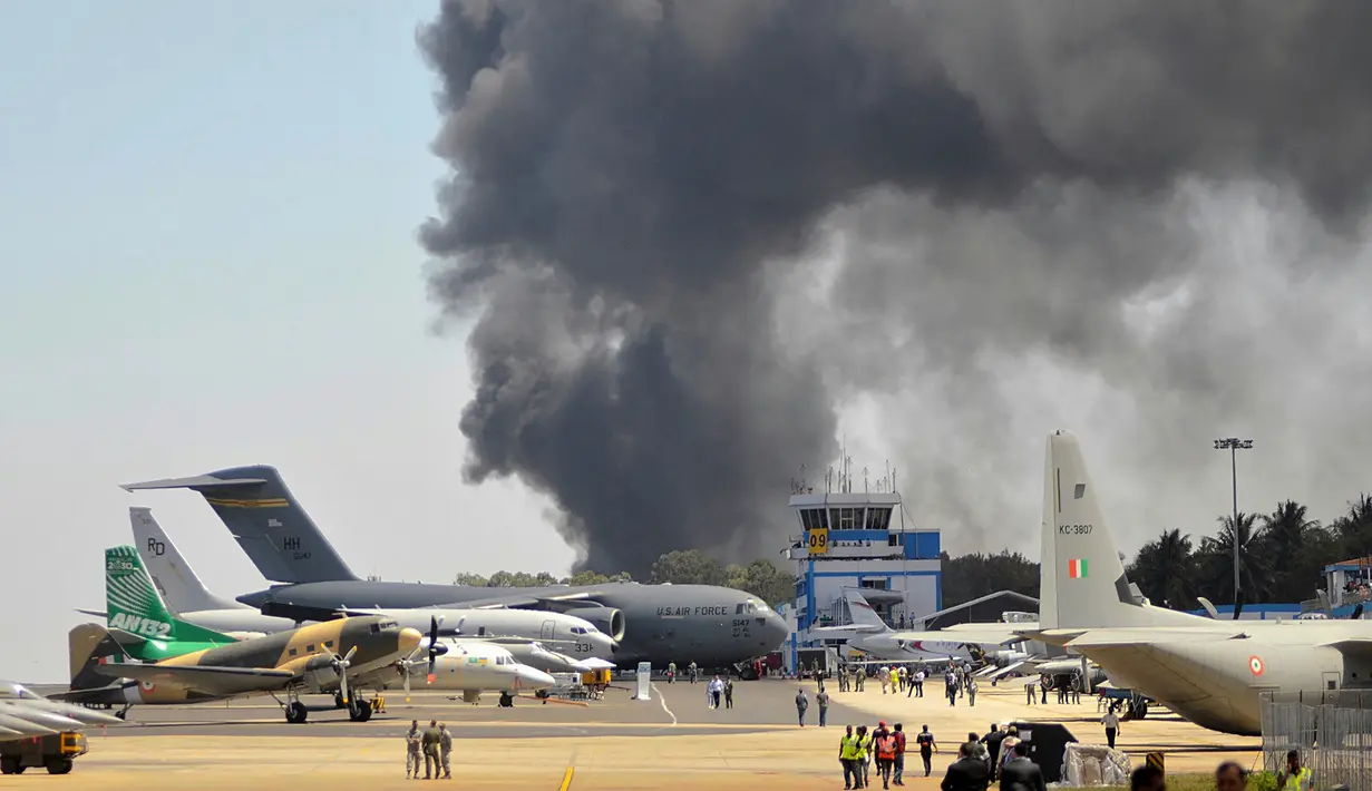 Asap hitam kebakaran mobil terlihat dari pameran dirgantara Aero India 2019, Bangalore, India, Sabtu (23/2). Aero India 2019 terganggu dengan adanya kebakaran tersebut. (STR/AFP)