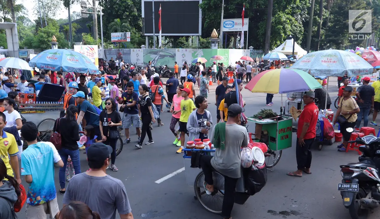 Penjaja makanan melintas saat pelaksanaan Car Free Day di kawasan Senayan, Jakarta, Minggu (8/10). Tidak adanya sekat dengan PKL, mengakibatkan aktivitas pengunjung yang ingin berolahraga kurang leluasa. (Liputan6.com/Fery Pradolo)