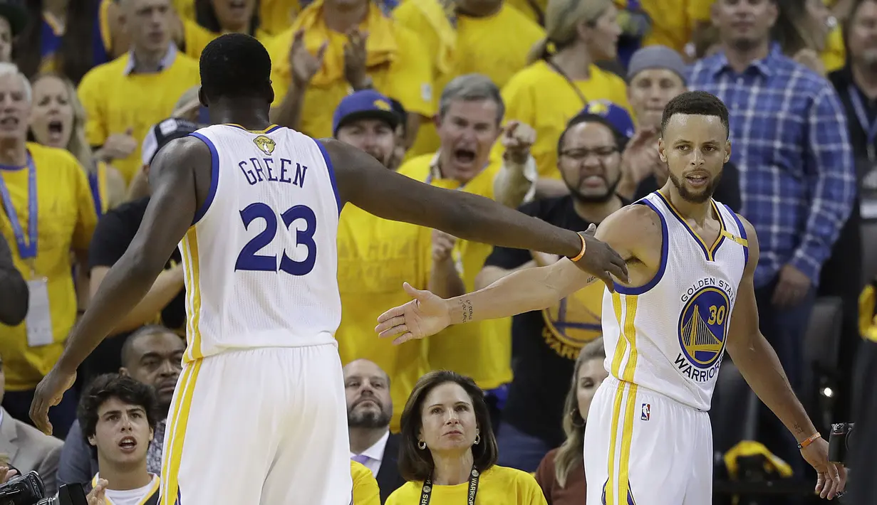 Pemain Warriors, Draymond Green (23) dan Stephen Curry (30) bersalaman saat gim kelima Final NBA 2017 melawan Cleveland di  Oracle Arena, Oakland, (12/6/2017). Warriors menang 129-120. (AP/Marcio Jose Sanchez)