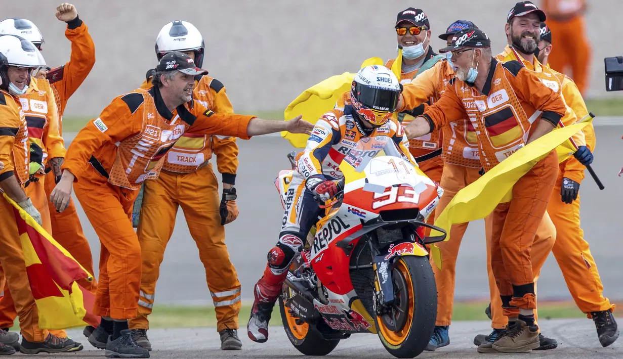 Para marshal merayakan kemenangan pembalap Marc Marquez pada balapan MotoGP di Sirkuit Sachsenring, Hohenstein-Ernstthal, Jerman, Minggu (20/6/2021). Marc Marquez mempertegas status sebagai raja Sachsenring usai memenangkan MotoGP Jerman 2021. (Jens Buettner/dpa via AP)